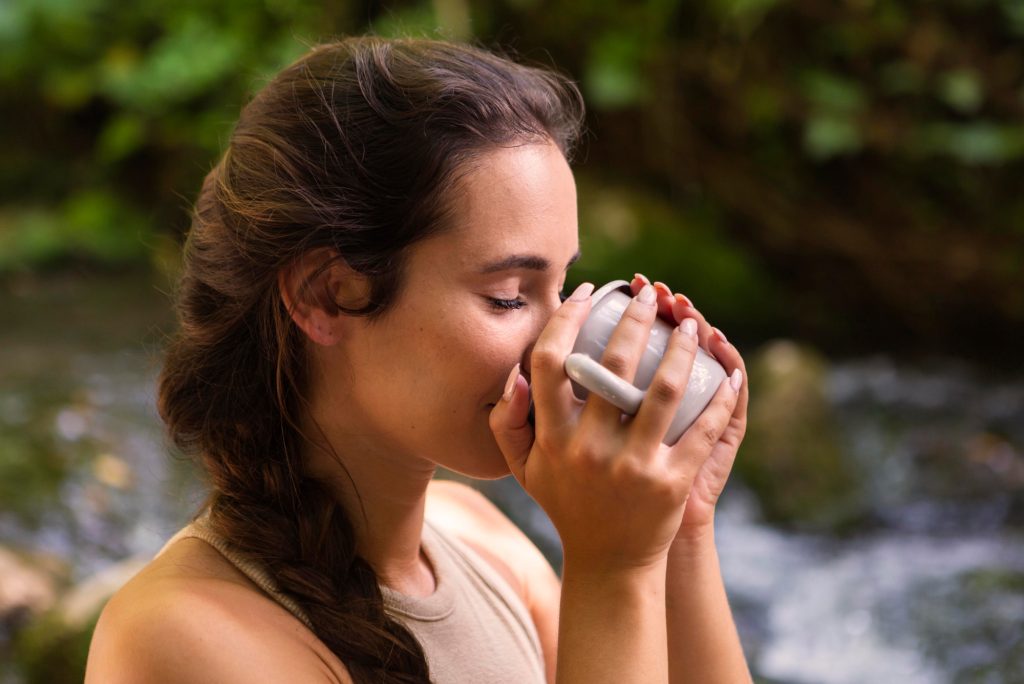 side view woman drinking out mug while outdoors nature